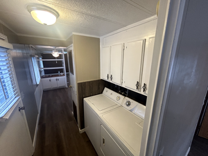 Laundry area featuring crown molding, dark wood-type flooring, cabinets, independent washer and dryer, and a textured ceiling