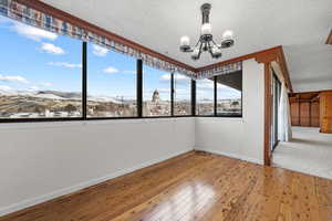 Empty room featuring wood-type flooring, a mountain view, a textured ceiling, and a chandelier