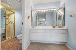 Bathroom featuring vanity, a shower with shower door, and toilet