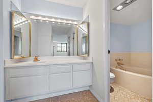 Bathroom with a washtub, vanity, and toilet