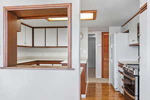 Kitchen featuring electric range, light hardwood / wood-style floors, and white cabinets