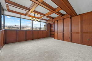 Unfurnished sunroom featuring an inviting chandelier, coffered ceiling, and beamed ceiling