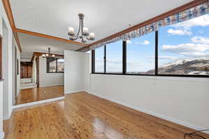 Spare room with an inviting chandelier, a mountain view, hardwood / wood-style flooring, and a textured ceiling