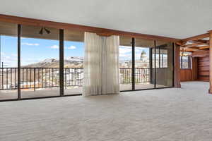 Unfurnished room featuring a mountain view, floor to ceiling windows, a textured ceiling, and carpet flooring