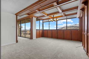 Unfurnished sunroom featuring coffered ceiling, beam ceiling, plenty of natural light, and an inviting chandelier