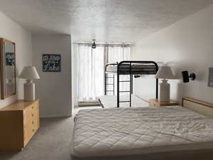 Carpeted bedroom with baseboard heating unit, and a textured ceiling