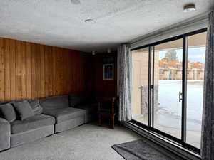 Carpeted living room featuring wooden walls and a textured ceiling