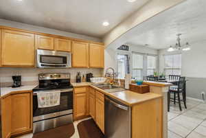 Kitchen featuring sink, appliances with stainless steel finishes, decorative light fixtures, kitchen peninsula