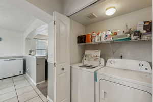 Washroom with light tile patterned flooring and washer and clothes dryer