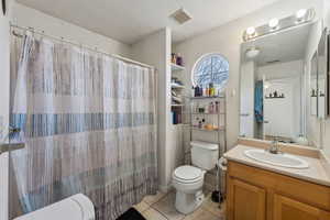 Bathroom featuring ceiling fan, vanity, curtained shower, tile patterned floors, and toilet