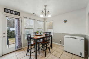 Tiled dining space featuring an inviting chandelier