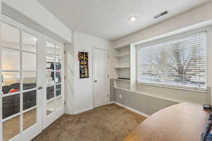 Carpeted office with french doors and a wealth of natural light