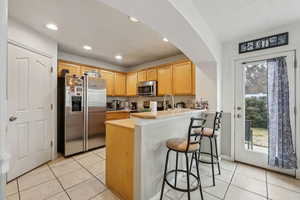 Kitchen featuring appliances with stainless steel finishes, a healthy amount of sunlight, a breakfast bar area, and kitchen peninsula