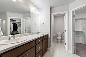 Bathroom featuring tile patterned floors, dual vanity, and toilet