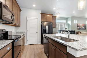 Kitchen single basin sink, large pantry, pendant lights, granite countertops, and black stainless appliances