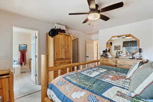 Tiled bedroom featuring connected bathroom and ceiling fan