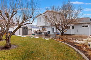 Back of house with a lawn, a patio area, and a shed