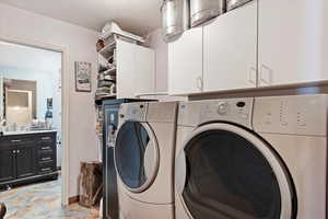 Laundry room featuring cabinets, a textured ceiling, and independent washer and dryer