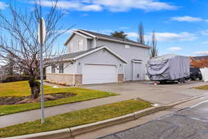 View of property featuring a garage and a front lawn