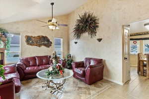 Living room featuring vaulted ceiling, plenty of natural light, and ceiling fan