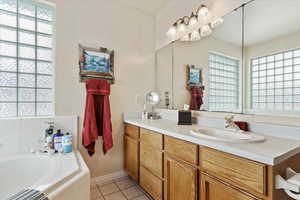 Bathroom featuring vanity, tile patterned flooring, and a relaxing tiled tub