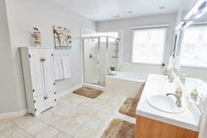 Bathroom with tile patterned floors, vanity, and shower with separate bathtub