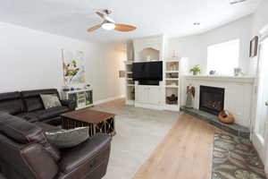 Living room featuring ceiling fan, light colored carpet, and a tiled fireplace