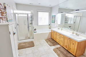 Bathroom featuring tile patterned flooring, vanity, and separate shower and tub