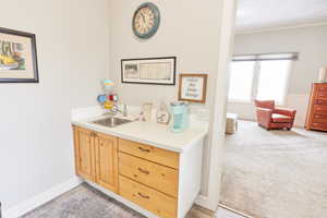 Casita - Bar with light brown cabinetry, sink, ornamental molding, and light colored carpet