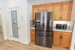 Kitchen with appliances with stainless steel finishes, a textured ceiling, light hardwood / wood-style flooring, and backsplash