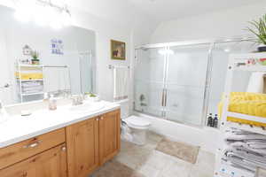 Full bathroom with vanity, tile patterned floors, shower / bath combination with glass door, and toilet