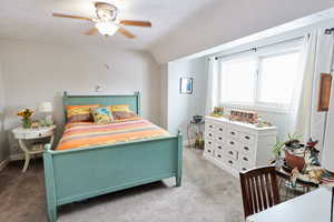 Bedroom featuring vaulted ceiling, light colored carpet, and ceiling fan