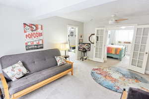 Carpeted living room featuring french doors and ceiling fan