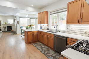 Kitchen with pendant lighting, sink, stainless steel dishwasher, kitchen peninsula, and light wood-type flooring