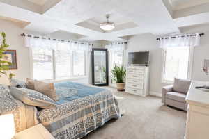 Bedroom with multiple windows, light colored carpet, and a textured ceiling