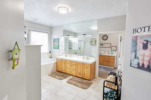 Bathroom with vanity, a textured ceiling, tile patterned floors, and separate shower and tub