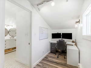 Office area with vaulted ceiling, wood-type flooring, sink, baseboard heating, and track lighting