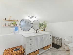 Bathroom with tile patterned flooring, vanity, lofted ceiling, and toilet