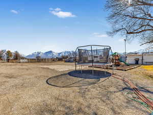 View of yard featuring a playground, a mountain view, and a trampoline