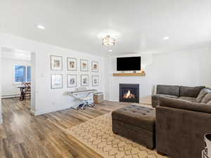 Living room featuring wood-type flooring, a fireplace, and a baseboard radiator