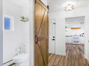 Bathroom featuring tasteful backsplash, hardwood / wood-style flooring, toilet, and baseboard heating