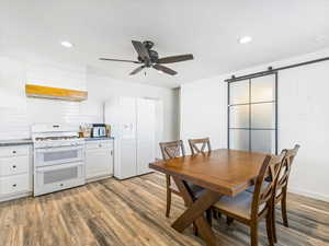 Dining space featuring ceiling fan, a barn door, and light hardwood / wood-style flooring