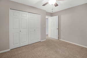 Unfurnished bedroom featuring carpet floors, ceiling fan, and a closet