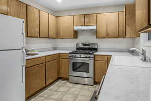 Kitchen with gas range, sink, and white fridge