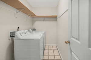 Clothes washing area with washing machine and dryer and light tile patterned floors