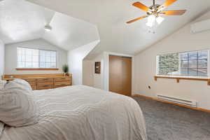 Carpeted bedroom with vaulted ceiling, a textured ceiling, a baseboard radiator, a closet, and a wall unit AC