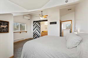 Carpeted bedroom featuring vaulted ceiling, a baseboard radiator, a wall mounted AC, a barn door, and a textured ceiling