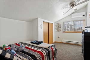 Carpeted bedroom with vaulted ceiling, an AC wall unit, a baseboard radiator, a closet, and ceiling fan