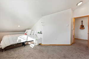 Bedroom featuring vaulted ceiling and carpet floors