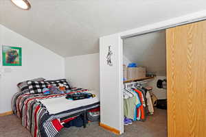 Bedroom featuring lofted ceiling, carpet floors, and a textured ceiling